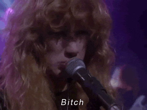 a close up of a man singing into a microphone with the word bitch written below him