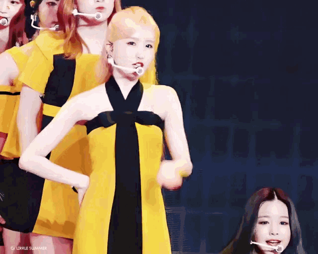 a girl in a yellow and black dress stands in front of a microphone with the words little summer written below her