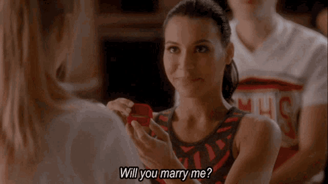 a woman is holding a box that says " will you marry me " on it