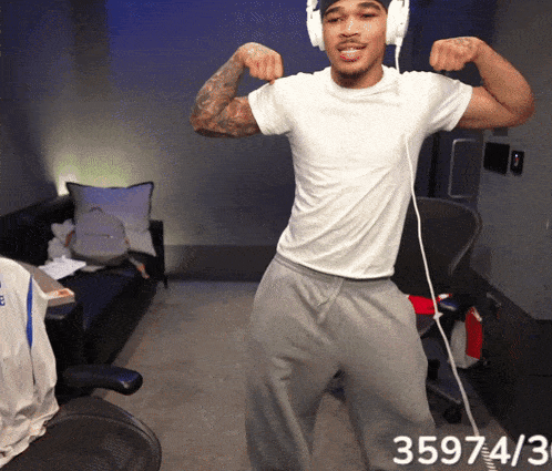 a man wearing headphones flexes his muscles in a room with the number 359743 on the bottom right