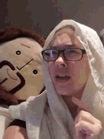 a woman wearing glasses is laying next to a stuffed monkey with the letter c on it