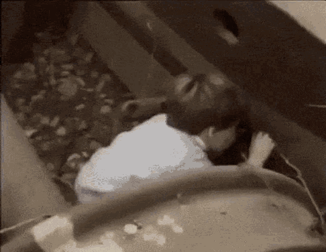 a man in a white shirt is crawling through a hole in the floor .