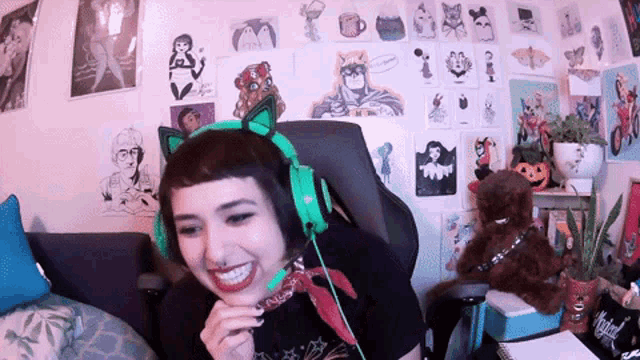 a woman wearing a cat ear headband is smiling in front of a wall covered in pictures
