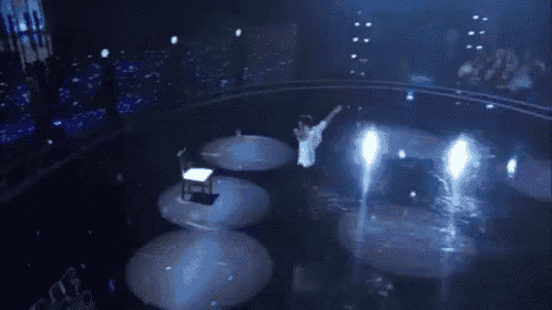 a person is playing a piano on a stage with a lot of lights behind them .