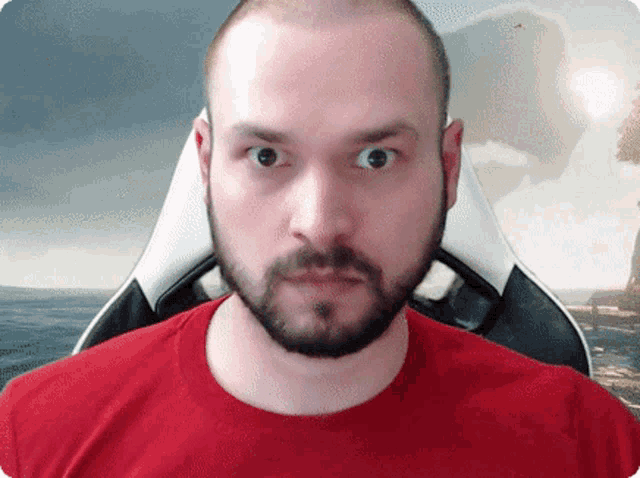 a man with a beard wearing a red shirt looks at the camera