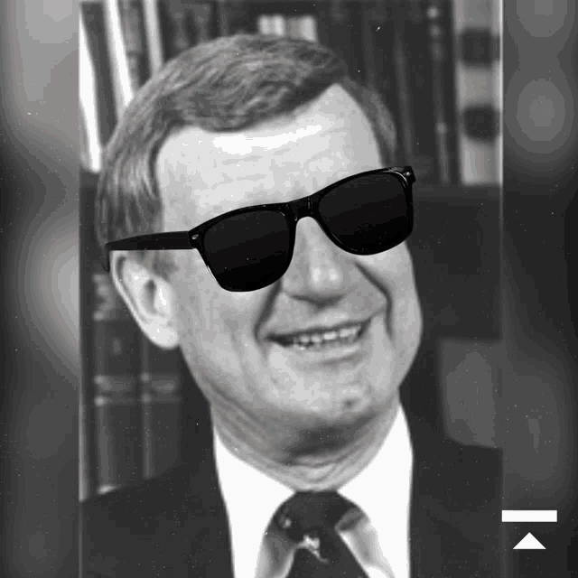 a man in a suit and tie is wearing sunglasses and smiling