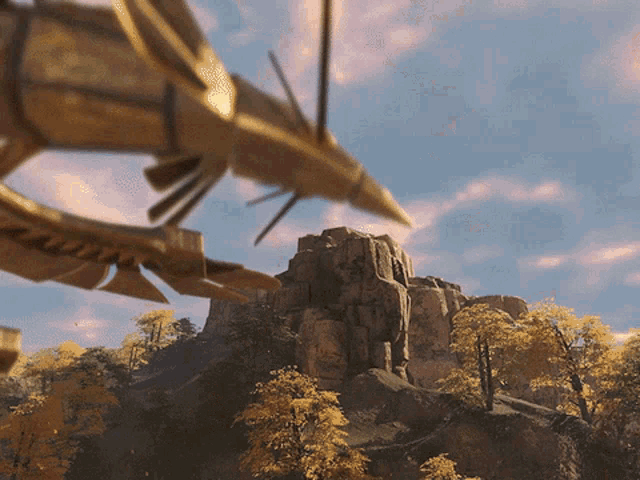 a statue of a dragon is flying over a mountain with trees in the foreground
