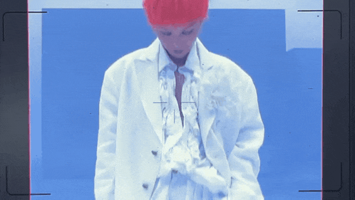 a person with red hair is standing in front of a blue wall