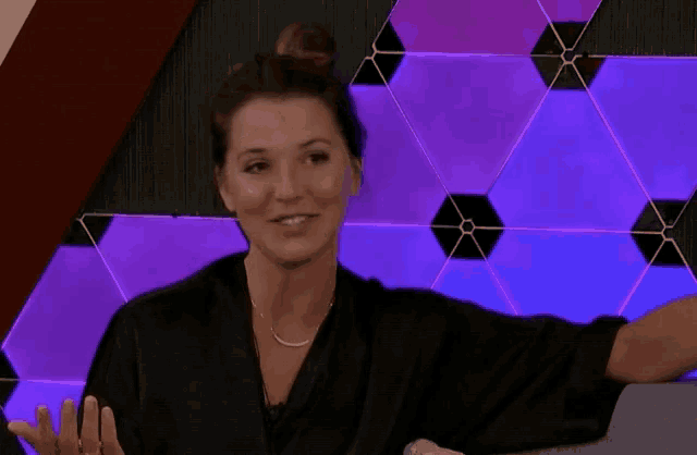 a woman is sitting in front of a wall with purple and blue lights