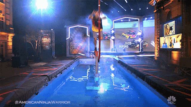 a nbc advertisement for american ninja warrior shows a person standing on a pole in the water