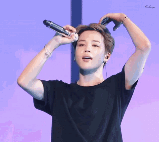 a man in a black shirt is holding a microphone in his hair