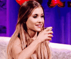 a woman is sitting on a couch drinking from a glass .