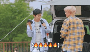 a man in a plaid shirt is talking to another man in front of a car