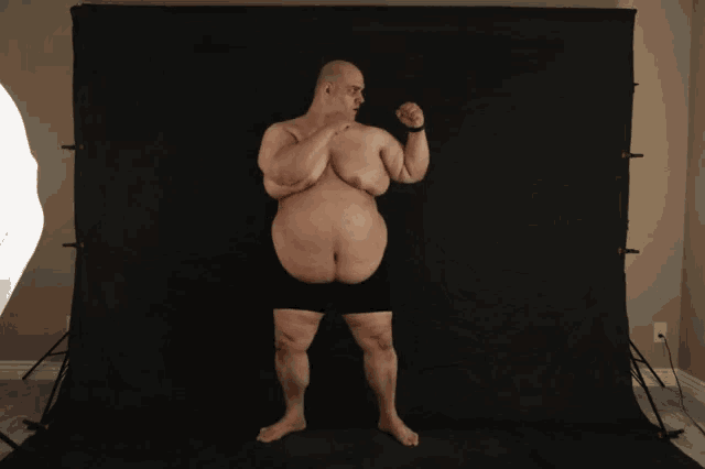 a man without a shirt is standing in front of a black background