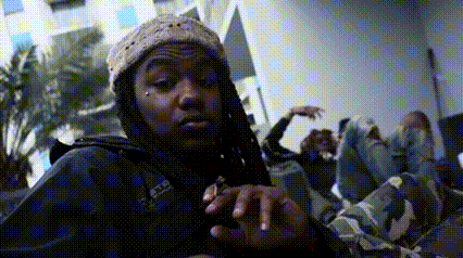 a man with dreadlocks is wearing a beanie and a jacket with the word adidas on the front