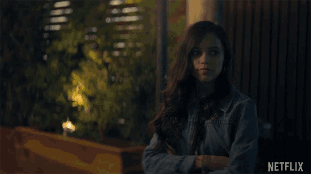 a woman in a denim jacket is standing in front of a netflix logo