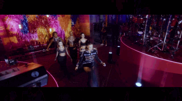 a group of people are dancing on a stage in front of drums