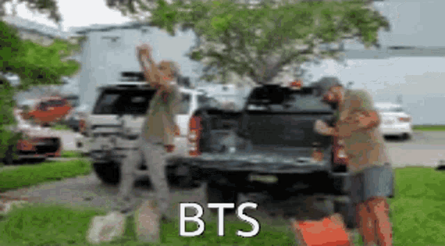 two men are standing in front of a truck with the word bts written on the back .