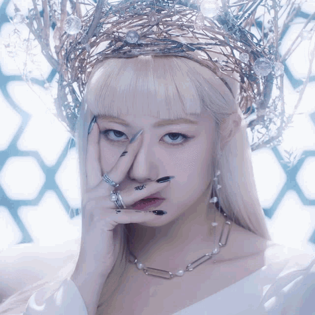a woman with a crown on her head is covering her face with her hands