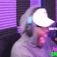a man wearing headphones and a hat is sitting in front of a microphone .