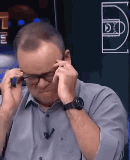 a man wearing glasses and a watch is covering his ears with his hands
