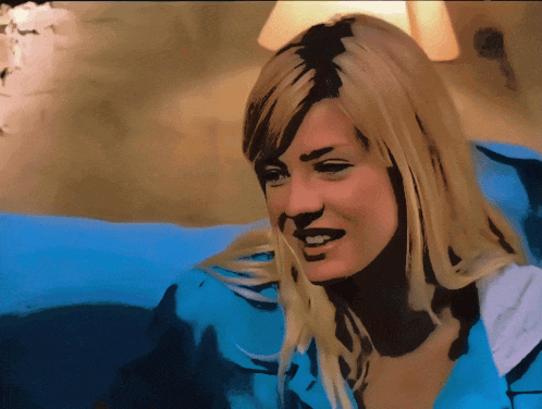 a blonde woman in a blue shirt is smiling