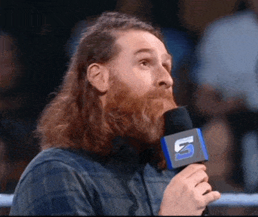 a man with a beard is holding a microphone with the letter n on it