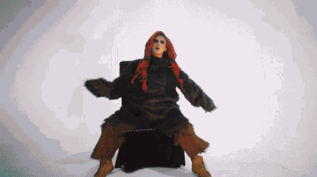 a woman with red hair is sitting on a chair with her arms outstretched