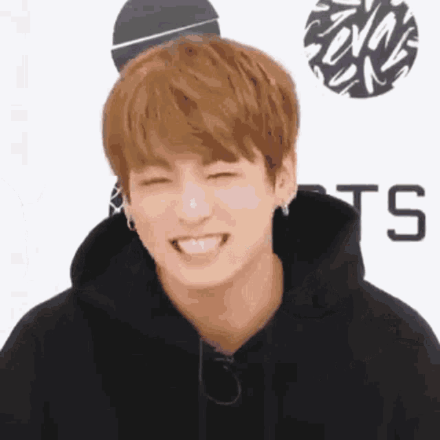 a close up of a person wearing a black hoodie smiling .
