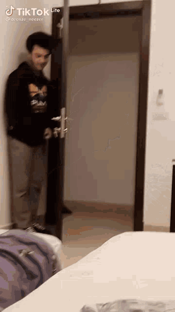 a man in a black hoodie is standing in a doorway .