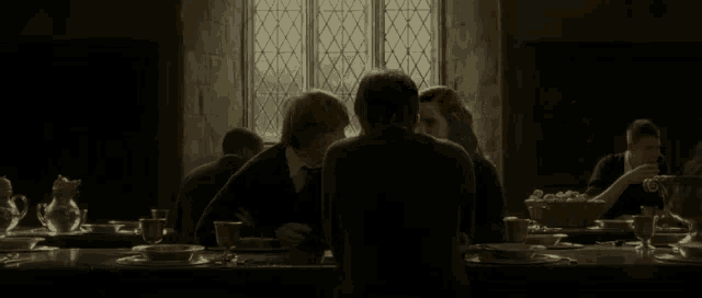 harry potter and ron weasley are sitting at a long table in a dark room