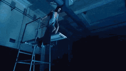 a woman in a dress is standing on a staircase in a dark room .