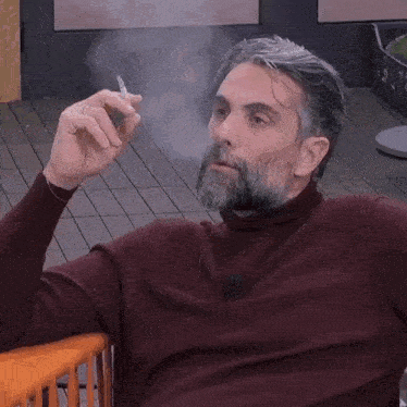 a man with a beard is smoking a cigar on a deck