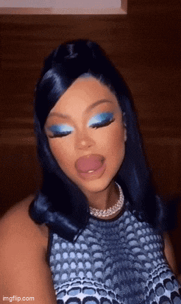 a woman with blue eye shadow and a necklace is sticking her tongue out .