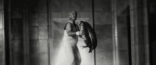 a black and white photo of a man holding a tire in a dark room .