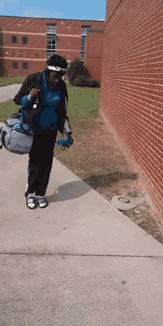 a woman walking down a sidewalk with a bag that says columbia