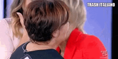 a woman is kissing another woman on the neck on a television screen .