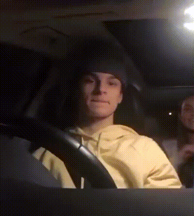 a man in a yellow sweatshirt is driving a car