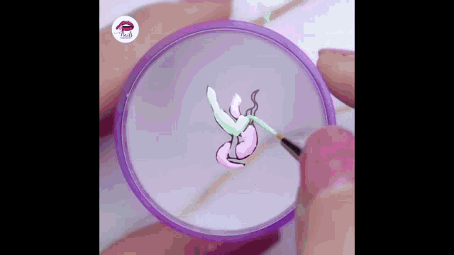 a close up of a person painting a flower on their nails with a brush .