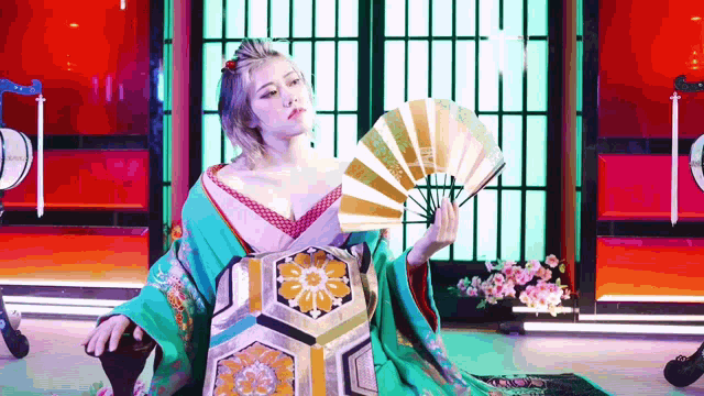 a woman in a kimono is holding a fan in her hand