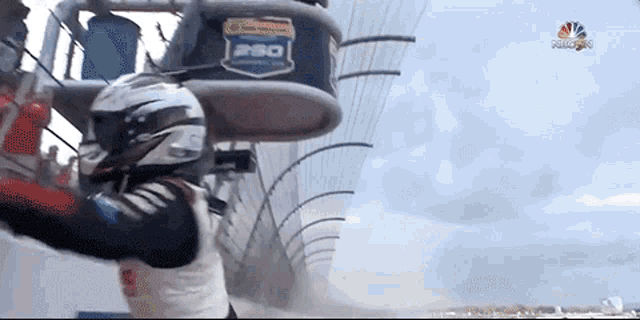 a man in a helmet stands in front of a nbc logo