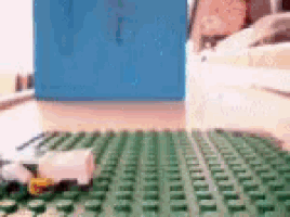 a blue box is sitting on a table next to a green lego mat .