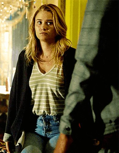 a woman wearing a striped shirt and jeans looks at a man
