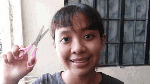 a girl holding a pair of pink scissors in her hand