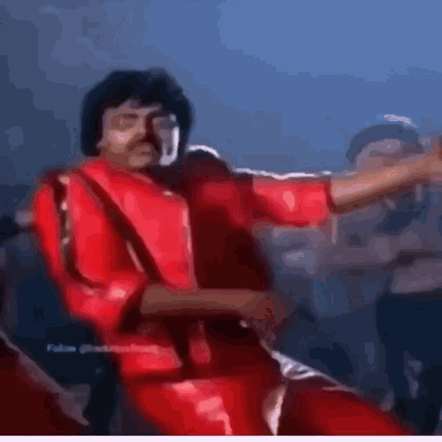 a man in a red life jacket is dancing in a crowd .