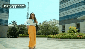 a woman in a white shirt and yellow pants is walking down a street .