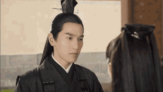 a man with a ponytail and a crown on his head stands next to a woman