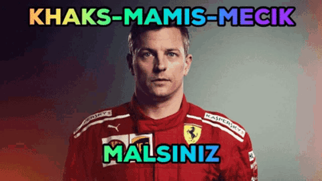 a man in a red ferrari racing suit stands in front of a sign that says khaks-mamis-mecik malsizin