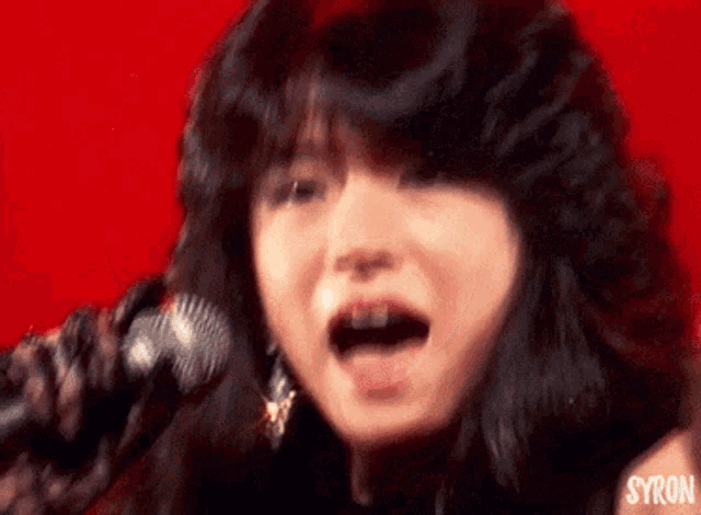a woman is singing into a microphone and the word syron is on the bottom