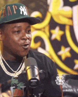 a man wearing a green hat with ny on it is talking into a microphone